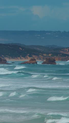 Powerful ocean waves break on limestone rock formations under daylight, static wide shot, natural light
