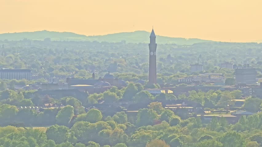 Aerial view of iconic Old Joe clock tower at the University of Birmingham surrounded by green trees and cityscape in summer golden light, UK. Birmingham, UK, Old Joe,