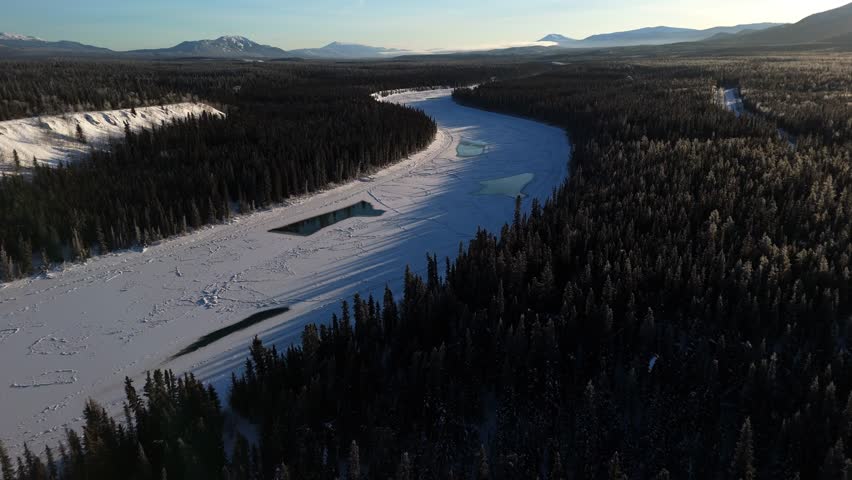 forests and frozen river near lake laberge in yukon territory, canada. aerial drone shot 4k video
