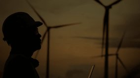 Silhouette engineer touching virtual data screen with wind turbines in background. Concept of clean energy, sustainability, and renewable power analysis. - Powered by Shutterstock - Get 15% off with code: PIKWIZARD15