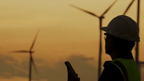 Silhouette of smart grid engineer holding mobile phone at wind farm. Concept of clean energy control, smart technology, and real-time renewable energy data. - Powered by Shutterstock - Get 15% off with code: PIKWIZARD15
