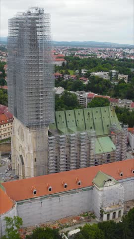 Cinematic orbit of Zagreb Cathedral in Croatia under restoration, highlighting its majestic twin spires, scaffolding, and intricate Gothic architecture surrounded by the historic cityscape