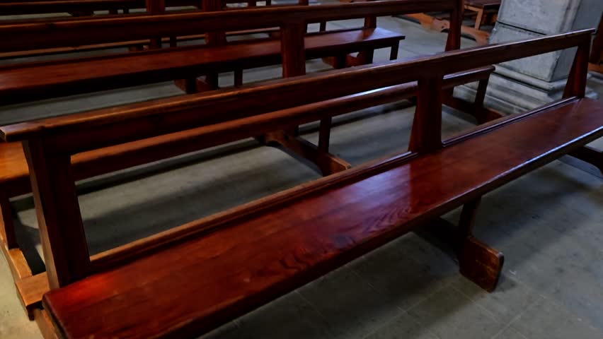 Empty rows of seating in a church captured with sunlight through windows, simple scene of stillness before ceremony.