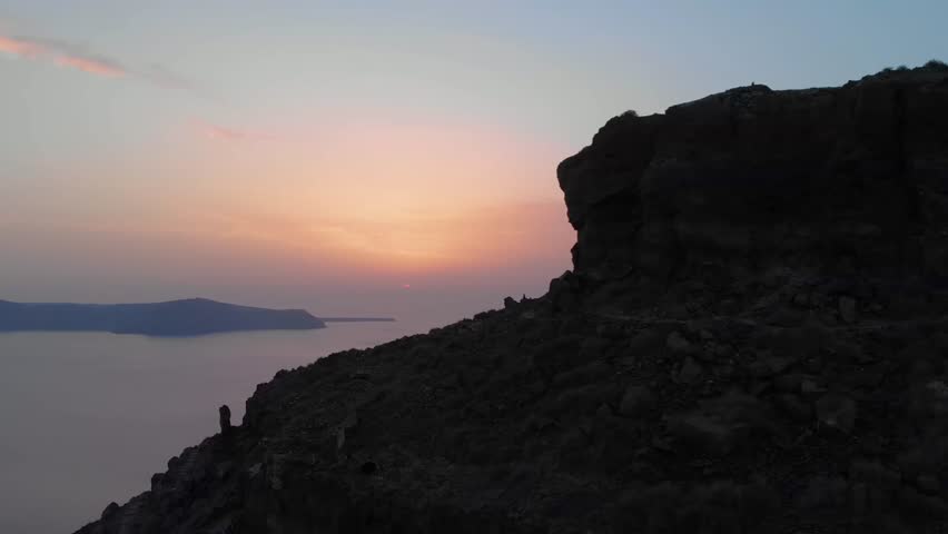 A sunset over the Aegean Sea and the caldera, viewed from the iconic Skaros Rock in Santorini, Greece.