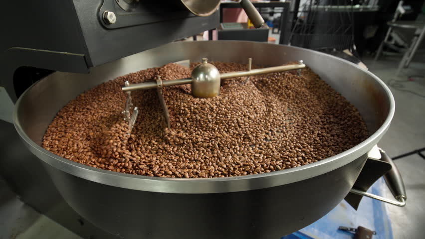 Fresh roasted coffee beans cooling in large industrial mixer machine roaster blend at modern factory aromatic brown grains blending mixing cocoa roasting closeup view of equipment production process