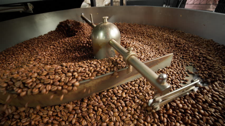 Fresh roasted coffee beans cooling in large industrial mixer machine roaster blend at modern factory aromatic brown grains blending mixing cocoa roasting closeup view of equipment production process