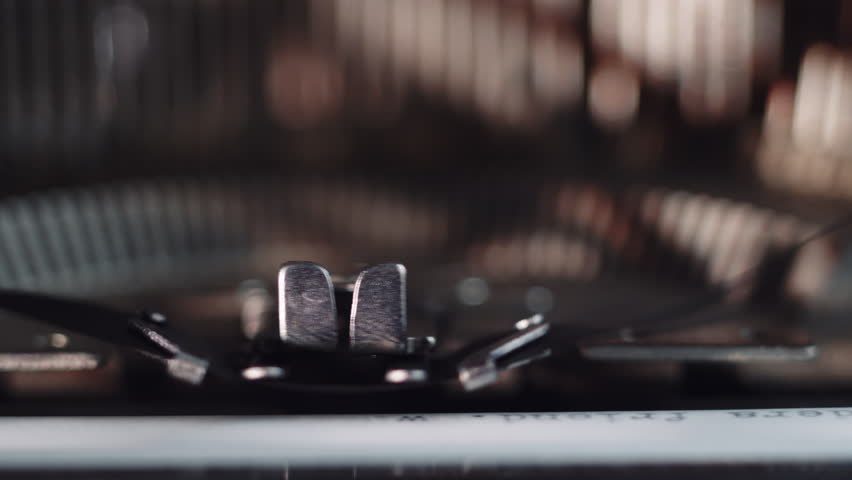 Close up typewriter. Type bars extreme close up print on paper. Cinematic shot of hammers typing letters on vintage typewriter.