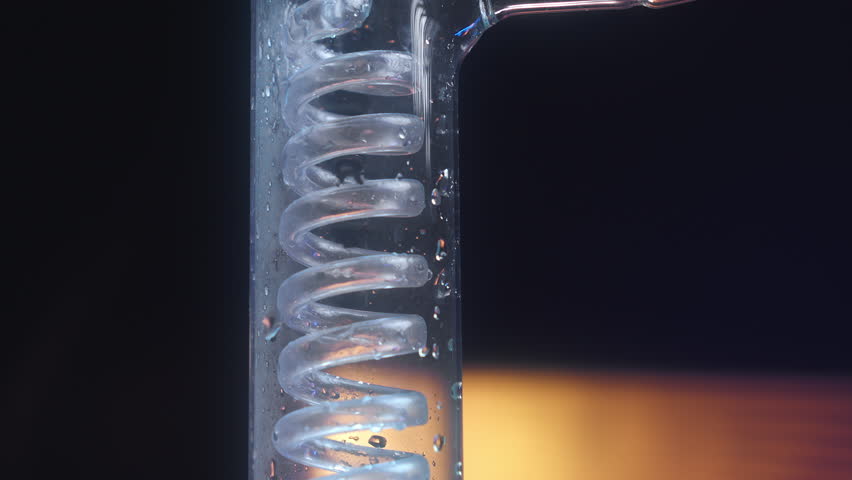 blue liquid flows through a glass flask in a coil.