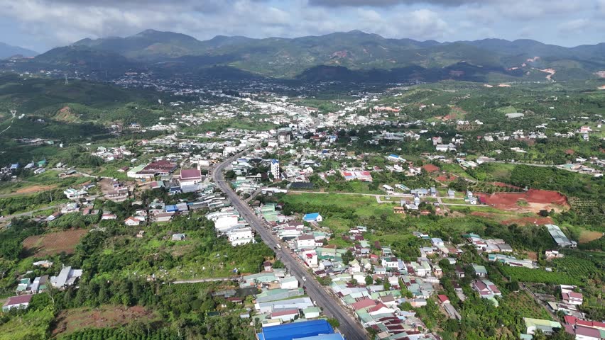 Aerial view of mountain valley town near Da Nang, Vietnam, showing curving road, lush hills, and the town spread out with buildings and greenery