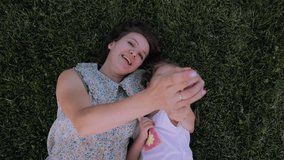Playful mother and daughter bonding on lush green grass, pointing and smiling, sharing joyful moment of familial connection and carefree happiness - Powered by Shutterstock - Get 15% off with code: PIKWIZARD15
