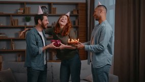 Three multiracial friends at home party birthday congratulation couple Caucasian woman with Latino American male congratulate man giving present box gift cake with candles blowing celebrate together - Powered by Shutterstock - Get 15% off with code: PIKWIZARD15