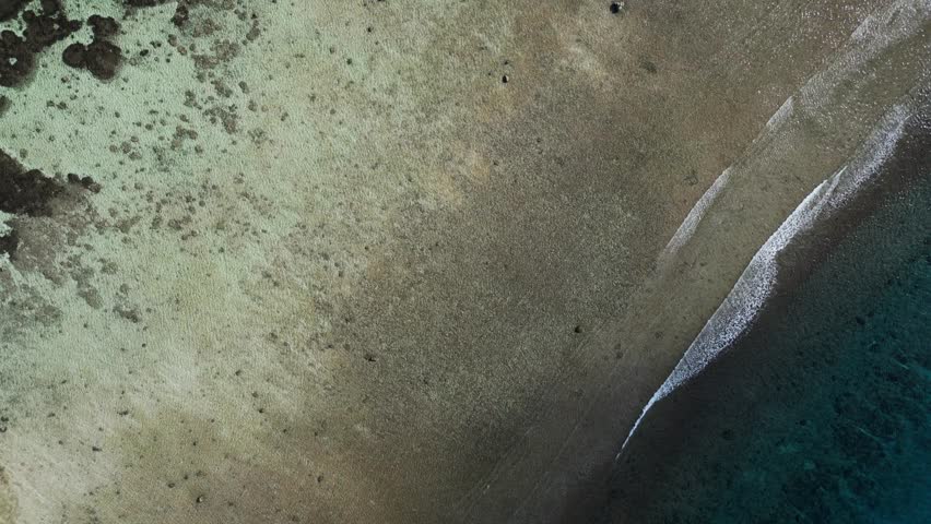 Aerial view tilt-up of Tumon Bay ocean waters reveals stunning Hilton hotel resort building with lush greenery at Guam, USA.