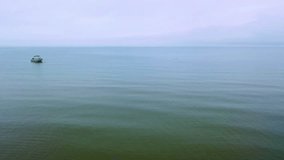 Sweeping drone shot of ocean waters and a boat as storm clouds loom overhead, casting shadows across waves while the horizon fades into gray mist, capturing the intensity of changing coastal weather - Powered by Shutterstock - Get 15% off with code: PIKWIZARD15