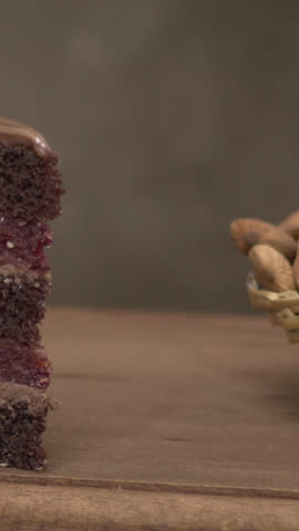 Pouring dark molten chocolate over a vanilla cupcake topped with coconut flakes, filmed in high definition on a wooden board, creating a delightful contrast of textures and flavors.