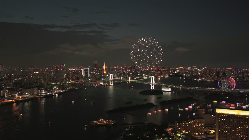 Summer festival fireworks burst over Tokyo Bay while Rainbow Bridge and Tokyo Tower shine. Cruise boats weave below and colorful reflections dance across the water in a dynamic cityscape