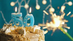 Birthday cake with number 50 candle and sparkling fireworks on blue background, slow-motion close-up, golden anniversary celebration, festive party dessert, milestone event photography. - Powered by Shutterstock - Get 15% off with code: PIKWIZARD15