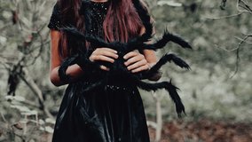 A young witch embraces Halloween magic while holding a large spider, surrounded by a dark, enchanted forest filled with intrigue - Powered by Shutterstock - Get 15% off with code: PIKWIZARD15