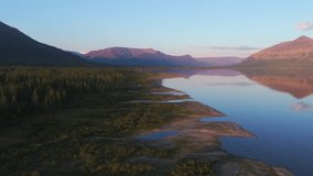 Aerial view of Lake Lama coastline at blue hour with pink mountain reflection across transparent water. Gentle river mouth, taiga margin and clear sky deliver rare Arctic travel atmosphere - Powered by Shutterstock - Get 15% off with code: PIKWIZARD15