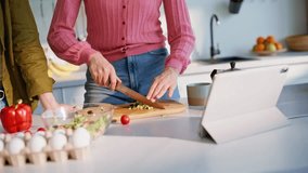 Woman hands chopping vegetables on wooden board in kitchen countertop closeup. Two girls preparing fresh salad watching online recipe on digital tablet. Focused girlfriends cooking together at home - Powered by Shutterstock - Get 15% off with code: PIKWIZARD15