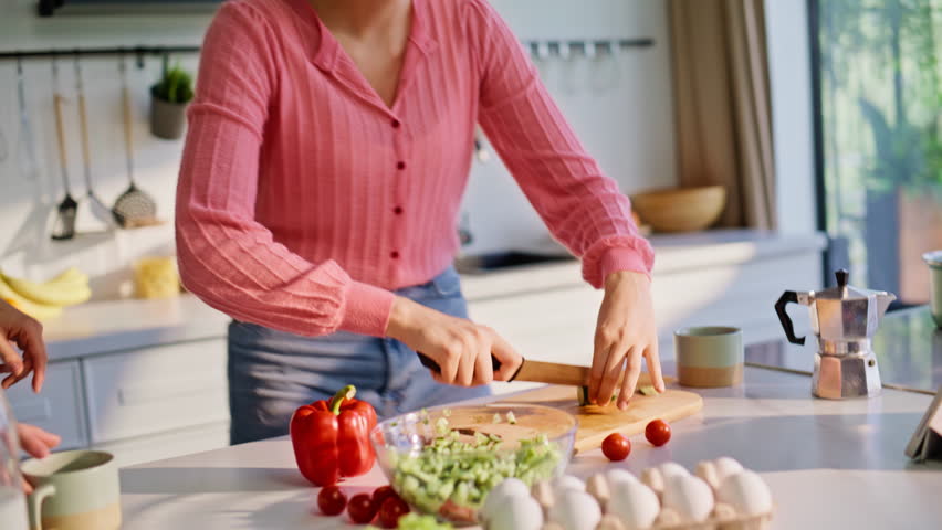 Closeup dancing ladies cooking at modern kitchen enjoying playful moment. Energetic pair smiling wide preparing ingredients. Joyful friends swaying to music sharing funny breakfast dance at apartment