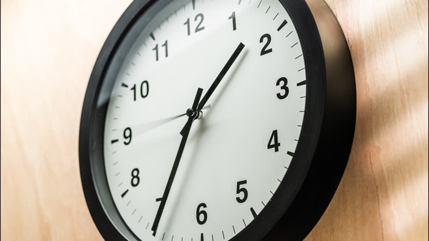 Timelapse video of a full 12-hour rotation of the hands of a classic black and white wall clock on wall.  A symbol of the transience of time and life.