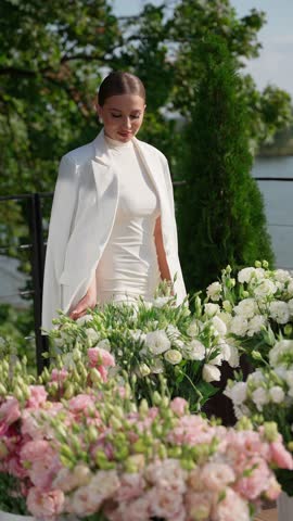 Stylish woman in elegant white dress surrounded by flowers. Elegant woman concept.