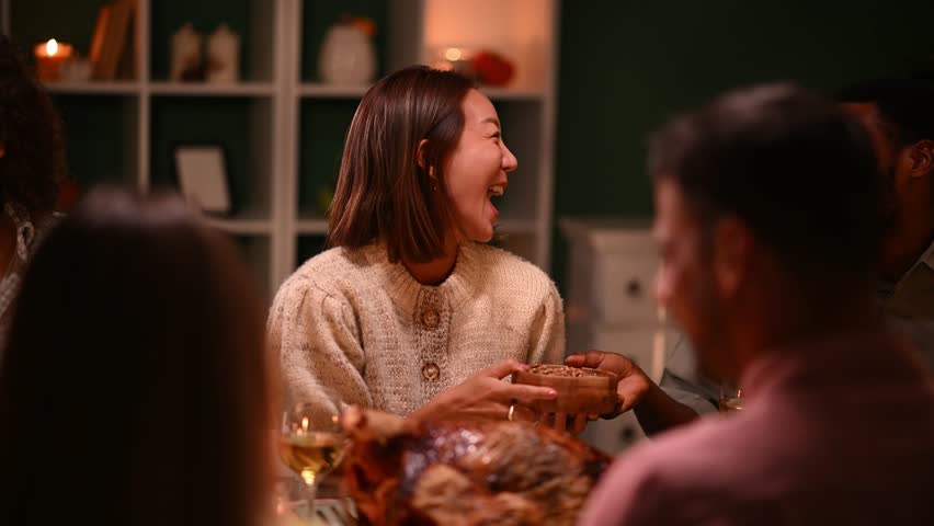 Friends sharing laughter and enjoying festive thanksgiving meal, gathering around table with warmth and joy during traditional holiday celebration