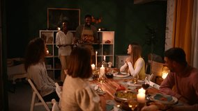 Diverse group of friends joyfully sharing roasted turkey, creating warm, candlelit thanksgiving dinner atmosphere inside cozy home environment - Powered by Shutterstock - Get 15% off with code: PIKWIZARD15