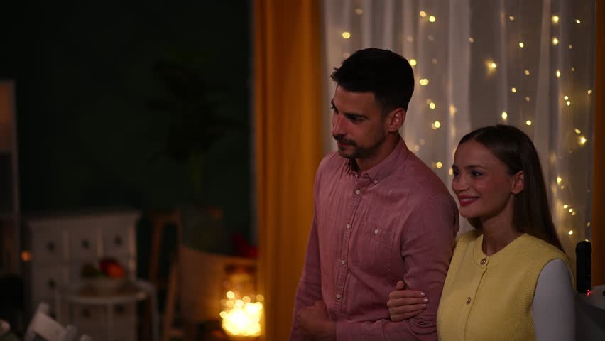 Group of cheerful young friends surprising woman during festive home gathering, sharing joyful hugs and laughter with genuine emotion and connection