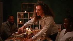 Multicultural friends sharing festive thanksgiving dinner, pouring wine, enjoying warm, candlelit gathering at home dining table with joyful connection - Powered by Shutterstock - Get 15% off with code: PIKWIZARD15