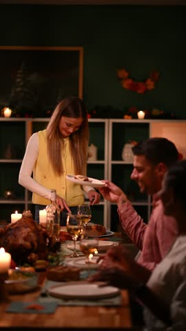 Woman serving turkey to family and friends during thanksgiving dinner, creating a warm and festive atmosphere