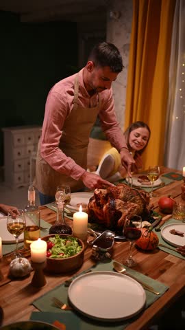 Family enjoying thanksgiving dinner, man carving turkey at table with candles, autumn decorations, and loved ones