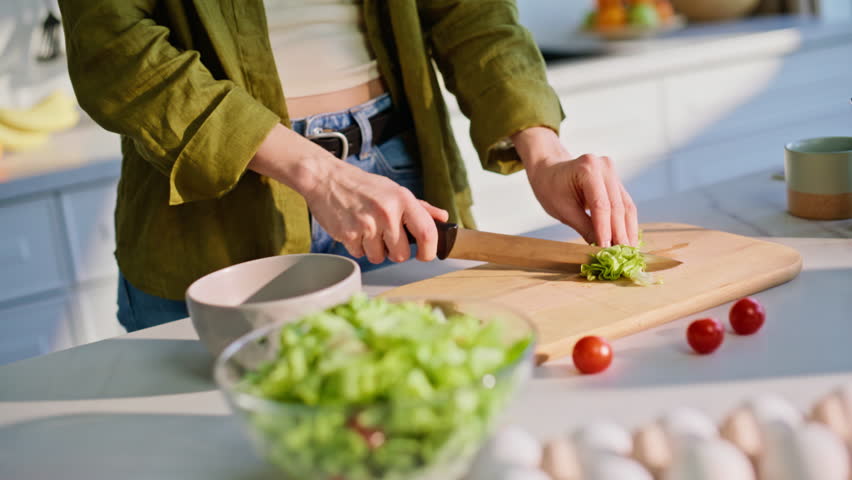Woman hands slicing salad on chopping board home kitchen closeup. Girl hands cutting fresh greens with knife cooking lunch. Food enthusiast preparing healthy vitamin ingredients for vegetarian meal 