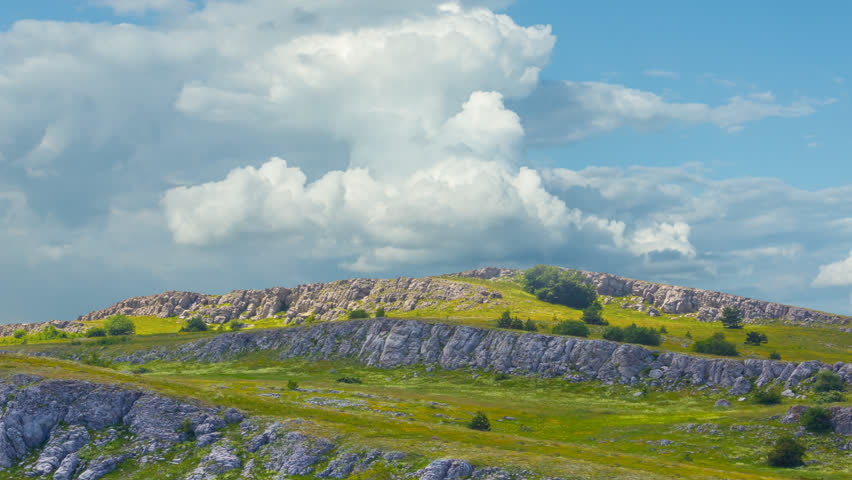 mountain ridge among green hills under blue cloudy sky time lapse scene