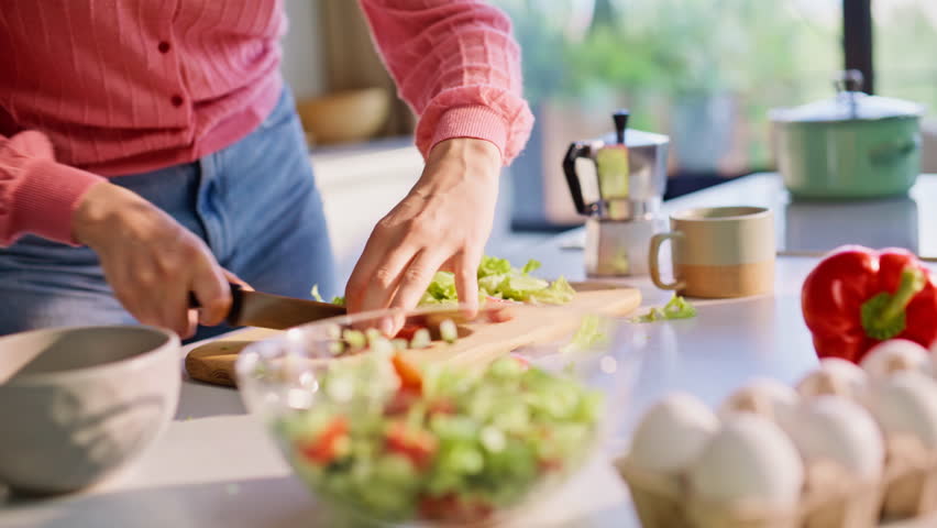 Lady hands cutting salad with precision near kitchen window closeup. Headphones model using dancing body enjoying cooking process. Joyful woman in earphones listening music. Smiling girl having fun
