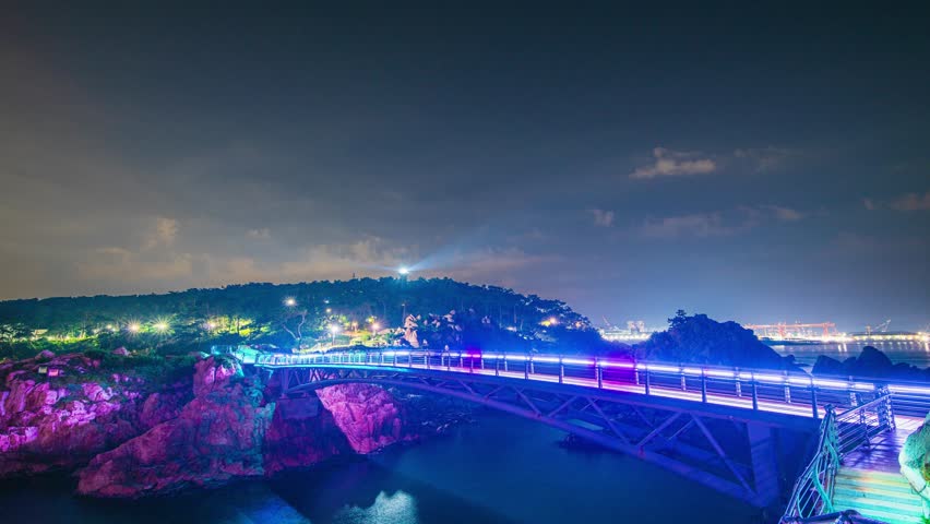 4K Timelapse of summer night scenery with waves, rocks and bridges crossing the island and colorful lights at Daewangam Park in Ulsan, South Korea.