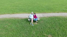 Older couple sitting on a bench in a grassy park on a sunny Day - Powered by Shutterstock - Get 15% off with code: PIKWIZARD15