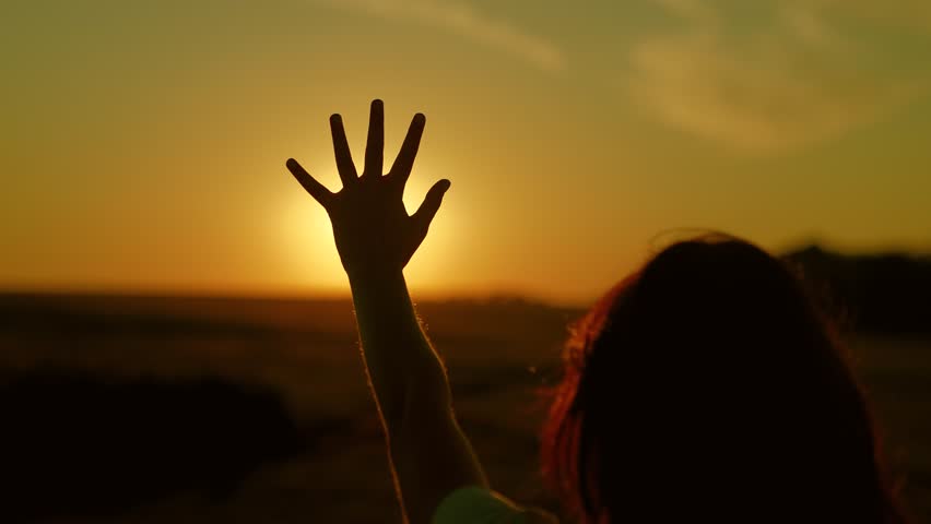 Girl child hand reaches out to beautiful sky sunset. Children prayer. Girl stretches out her hand to beautiful sun, dreams in nature. Teenager dreams, hopes stretches his arms to sky. Child is playing