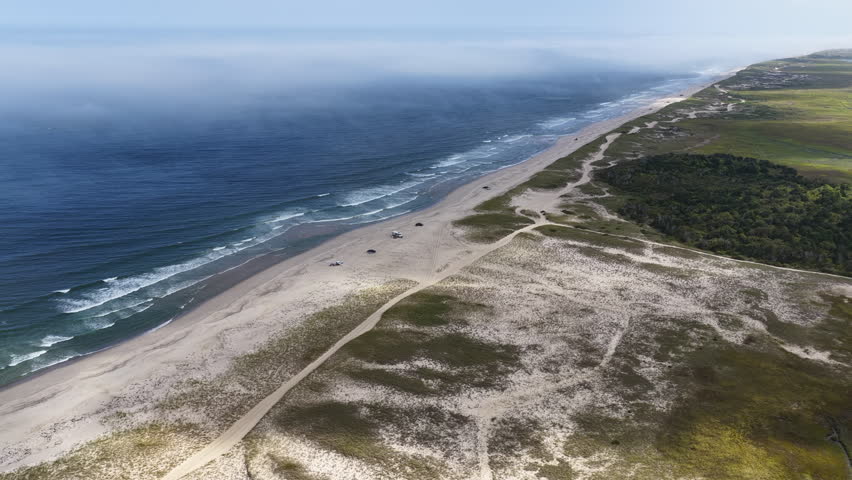 Clouds drift above scenic Nauset Beach in Orleans, Cape Cod, Massachusetts. This aesthetic public beach is a popular destination for people on vacation during summer months. 