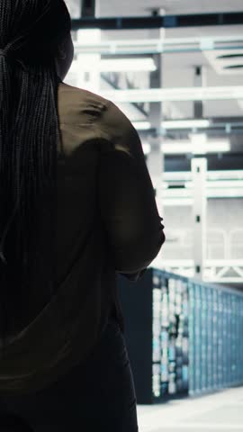 Vertical video Woman walking through data center server rows, implementing advanced cooling and power management solutions. IT expert overseeing server farm, reducing energy consumption, camera A