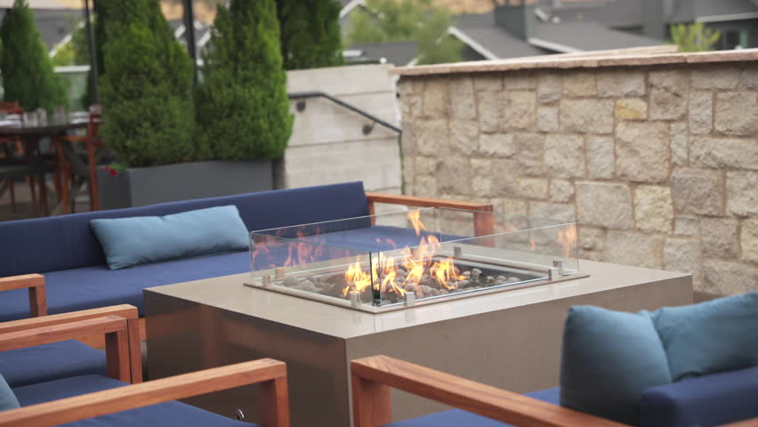 Stylish outdoor lounge features a contemporary fire pit surrounded by comfortable seating. The area is perfect for relaxation and socializing during cool evenings.