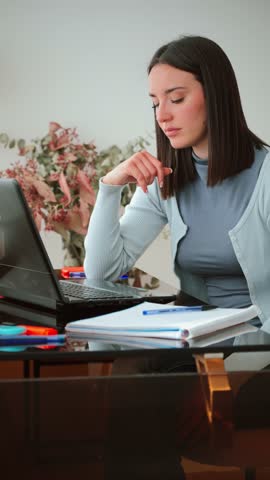 A young woman looking frustrated while working on her laptop at home, showing signs of sadness and stress on her face as she attempts to concentrate on her studies and tackle her academic tasks