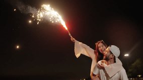 Happy man and woman travel the sea on summer beach holiday vacation. Asian family couple enjoy and fun outdoor active lifestyle playing sparkler fireworks together on tropical beach at night. - Powered by Shutterstock - Get 15% off with code: PIKWIZARD15