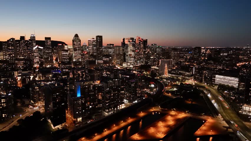 Montreal skyline at dusk, city lights reflecting over water in Grifintown and downtown. g.