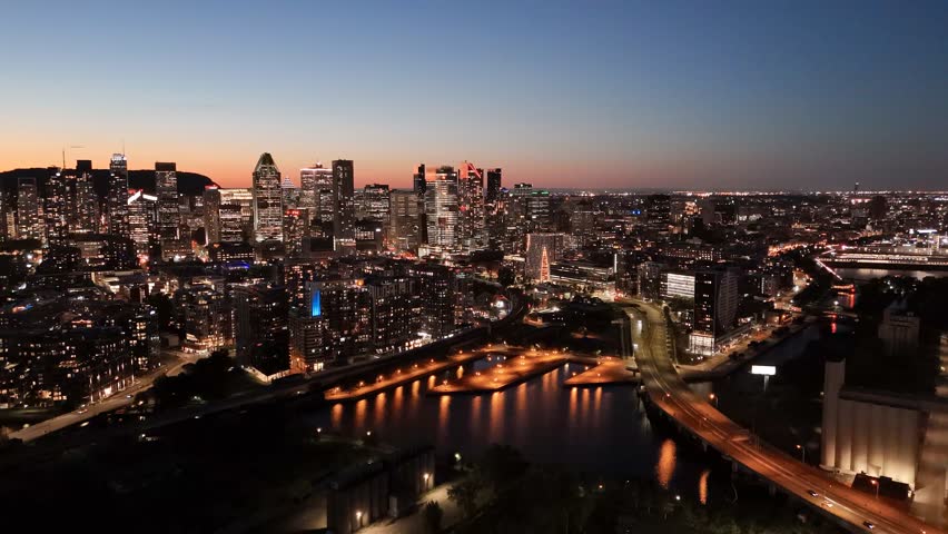Montreal skyline at dusk, city lights reflecting over water in Grifintown and downtown. g.