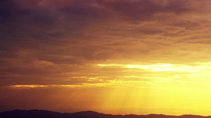 Beautiful sunset with golden light shining through the clouds over the mountains