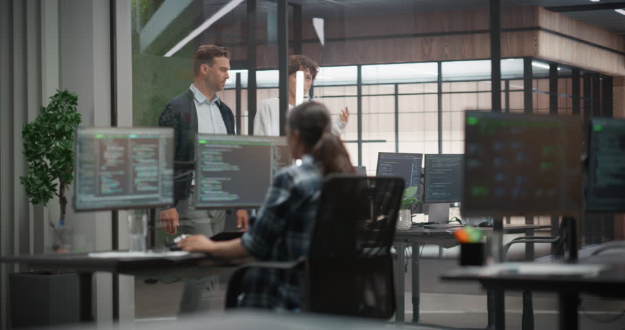 Male and Female Colleagues Walking in Hallway in Office, Talking and Using a Tablet Computer. Young Managers Discussing Work Assignments on a Software Development Project for an E-Commerce Company