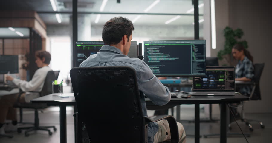 Portrait of a Young Handsome Software Engineer Turning to Look at a Camera, Pausing From Using a Desktop Computer in Office. Successful Information Technology Manager Working on Technology Projects