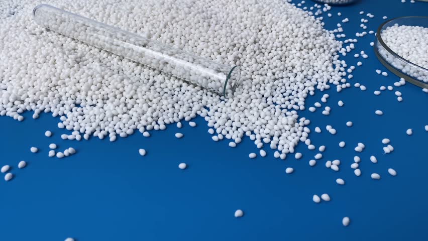 Glass flasks with white thermoplastic granules and petri dish for chemical experiments against the background of other laboratory glassware. Plastic raw granules materials for industry.
