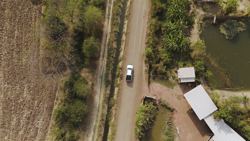 Aerial drone footage of a pickup truck driving on a rural road through countryside landscape. Scenic view of travel, transportation, and freedom in nature